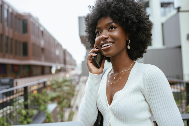 Mujer afro negra hablando por teléfono móvil en la ciudad