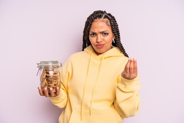 Mujer afro negra haciendo capice o gesto de dinero, diciéndole que pague. concepto de galletas