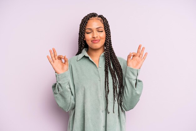 Mujer afro negra que parece concentrada y meditando sintiéndose satisfecha y relajada pensando o tomando una decisión