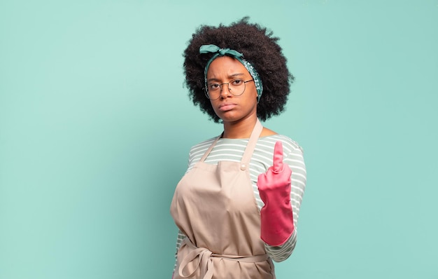 Mujer afro negra que se siente enojada, molesta, rebelde y agresiva, moviendo el dedo medio, contraatacando. concepto de limpieza ... concepto de hogar