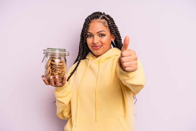 Mujer afro negra que se siente orgullosa sonriendo positivamente con el concepto de cookies de pulgares arriba