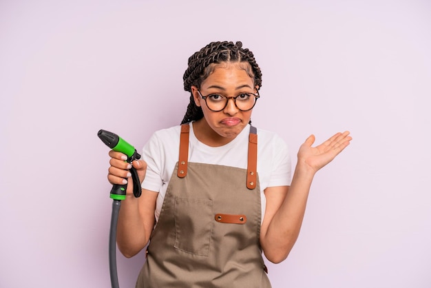 mujer afro negra que se siente perpleja, confundida y dubitativa. concepto de manguera de jardinero