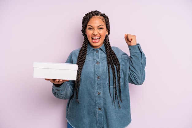 Mujer afro negra que se siente sorprendida, riendo y celebrando el éxito. concepto de caja de paquetes