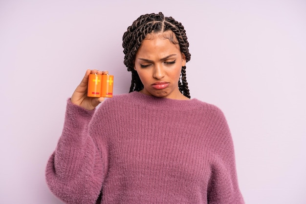 Mujer afro negra que se siente triste y quejumbrosa con una mirada infeliz y un concepto de batería llorando