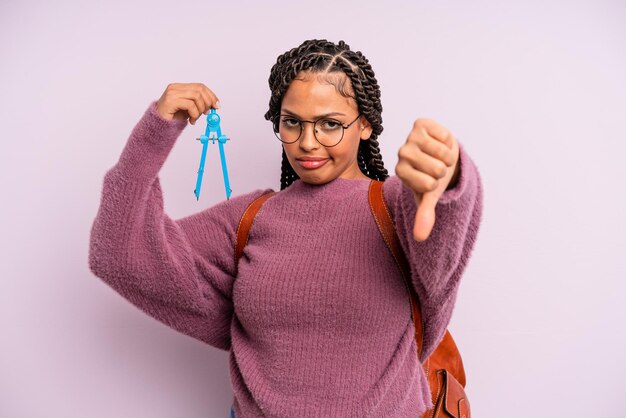 Mujer afro negra sintiéndose cruzada, mostrando los pulgares hacia abajo. medir el concepto de estudiante de brújula