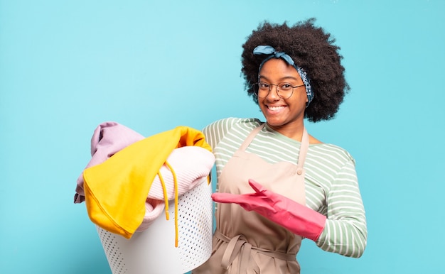 Mujer afro negra sonriendo alegremente, sintiéndose feliz y mostrando un concepto en el espacio de la copia con la palma de la mano. concepto de limpieza ... concepto de hogar