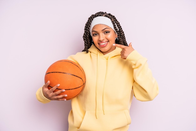 mujer afro negra sonriendo con confianza apuntando a su propia sonrisa amplia. concepto de baloncesto