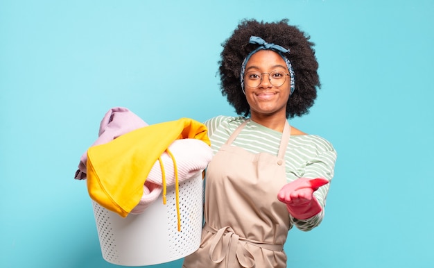 Mujer afro negra sonriendo felizmente con mirada amistosa, segura y positiva, ofreciendo y mostrando un objeto o concepto. concepto de limpieza. concepto de hogar