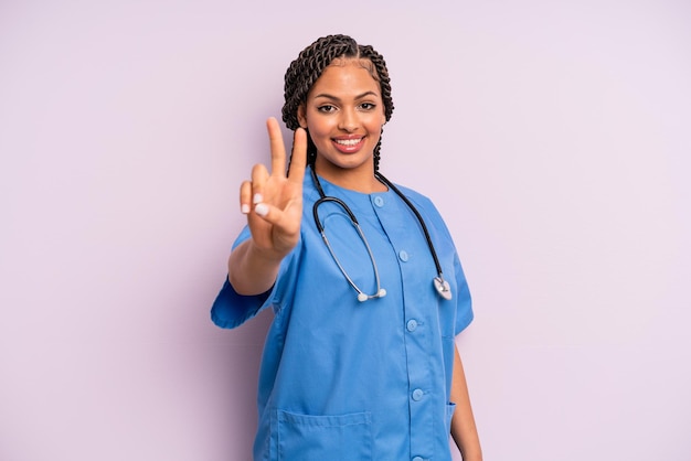 Mujer afro negra sonriendo y luciendo feliz, gestando victoria o paz. concepto de enfermera