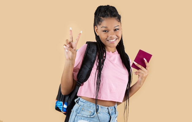 Mujer afro con pasaporte y mochila sobre fondo amarillo