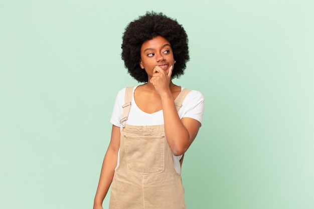 Mujer afro pensando, sintiéndose dudoso y confundido, con diferentes opciones, preguntándose qué decisión tomar concepto de chef