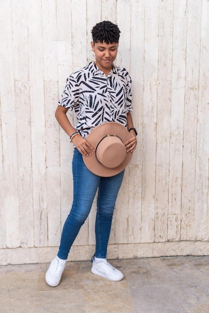 Mujer afro de pie contra la pared en la ciudad