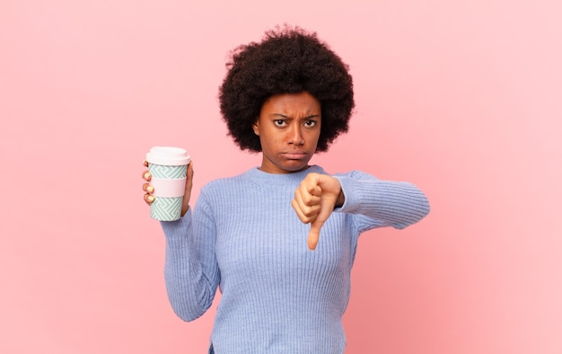 Mujer afro que se siente enfadada, enojada, molesta, decepcionada o disgustada, mostrando el pulgar hacia abajo con una mirada seria. concepto de cafe