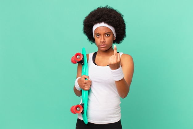 Mujer afro que se siente enojada, molesta, rebelde y agresiva, moviendo el dedo medio, contraatacando. concepto de patineta