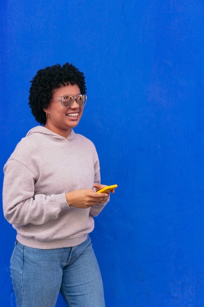 Mujer afro riendo delante de un fondo azul.