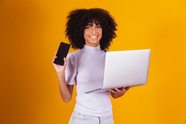 Mujer afro sosteniendo un celular en la mano y la otra con un cuaderno