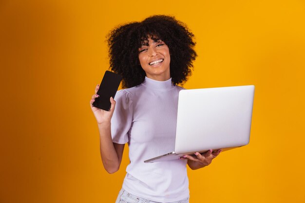 Mujer afro sosteniendo un celular en la mano y la otra con un cuaderno