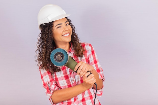 Mujer afro sosteniendo una lijadora eléctrica. concepto de material de construcción