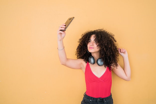 Foto mujer afro tomando selfies con teléfono.