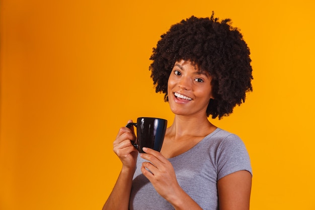 Mujer afro tomando té en amarillo