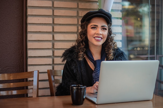 Mujer afro trabajando de forma remota usando su computadora portátil.