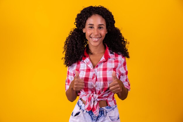 Mujer afro vestida con traje de festa junina con el pulgar hacia arriba