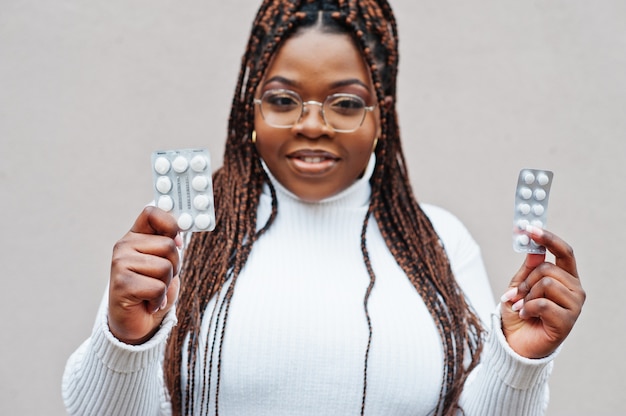 Mujer afroamericana en anteojos muestran pastillas.
