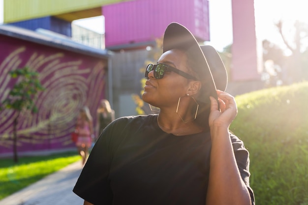 Mujer afroamericana en un área urbana de la ciudad sonriendo generación z o chica hipster milenaria posando