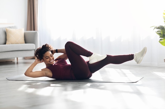 Mujer afroamericana atlética haciendo ejercicio en la alfombra de fitness en casa