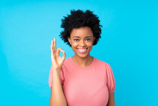 Mujer afroamericana en azul aislado mostrando un signo de ok con los dedos