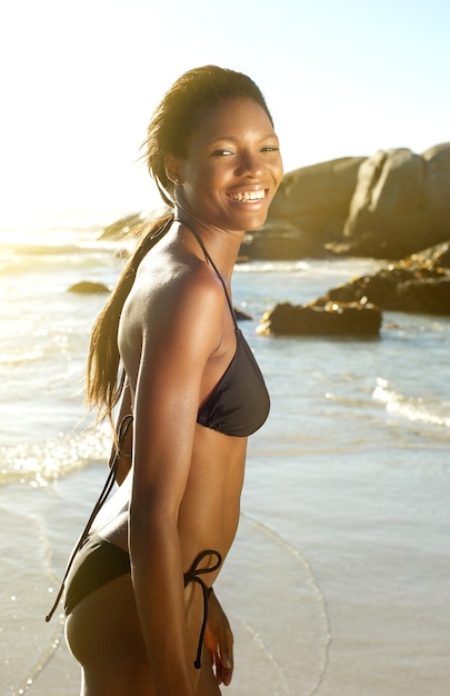 Mujer afroamericana en bikini sonriendo en la playa