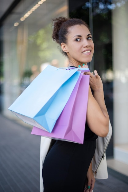 Mujer afroamericana con una bolsa azul y violeta sobre su hombro mirando hacia afuera