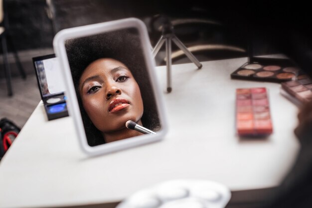 Mujer afroamericana con cabello rizado con aspecto positivo mientras graba video