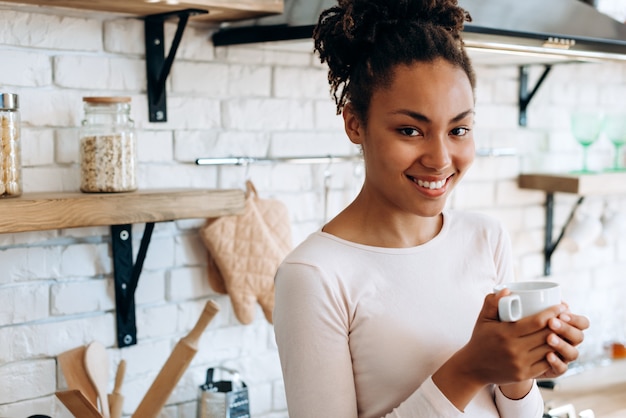 Mujer afroamericana con un café en la cocina