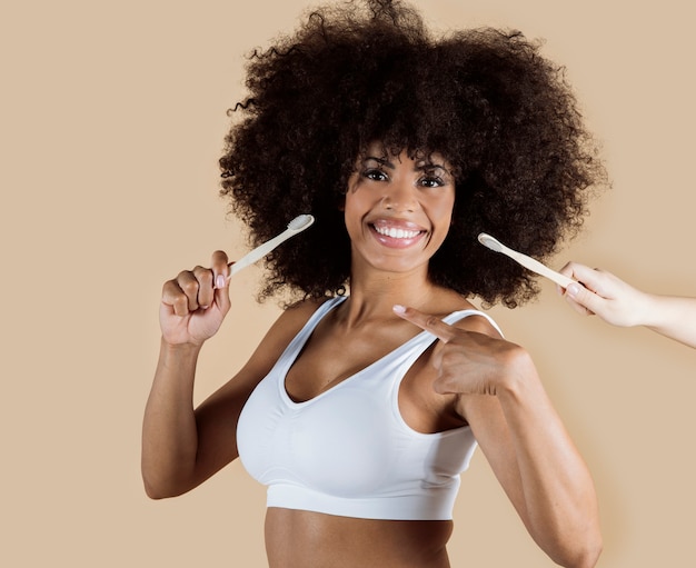 Mujer afroamericana con cepillo de dientes, cosméticos en crema, belleza spa, fondo beige