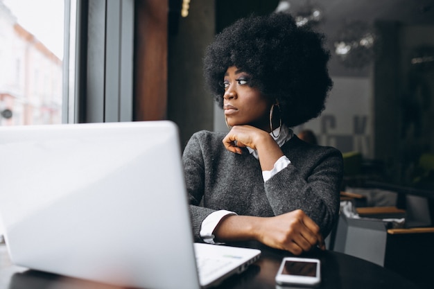 Mujer afroamericana con la computadora portátil en un café