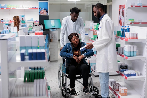 Mujer afroamericana con discapacidad comprando en farmacia, farmacéutica recomendando medicamentos. Medicamentos minoristas, clientes y consultores de farmacias hablando, todo el equipo negro