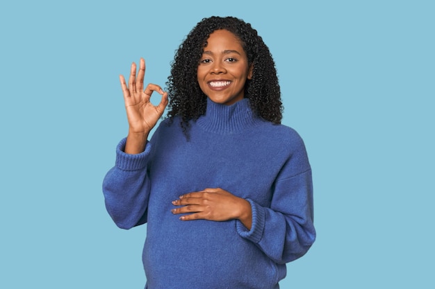 Mujer afroamericana embarazada en el estudio alegre y segura mostrando un gesto de OK