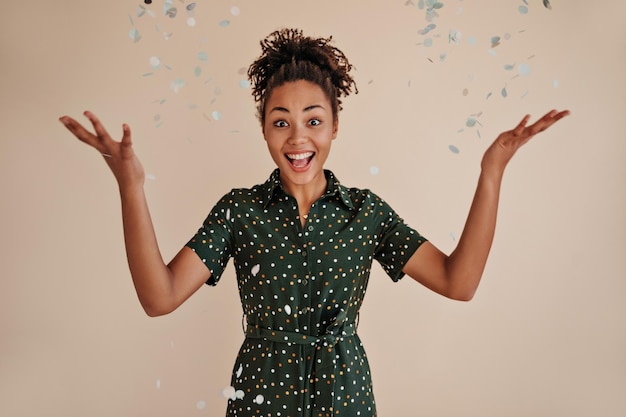 Mujer afroamericana emocionada tirando confeti Foto de estudio de una chica negra riéndose aislada de fondo beige