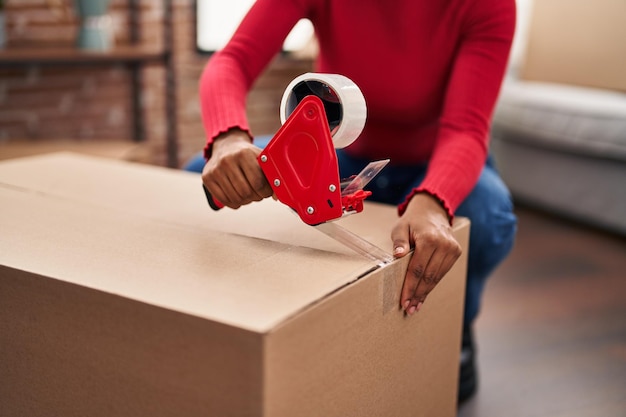 Mujer afroamericana empacando una caja de cartón en un nuevo hogar