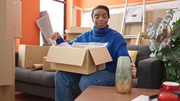 Mujer afroamericana empacando una caja de cartón en un nuevo hogar