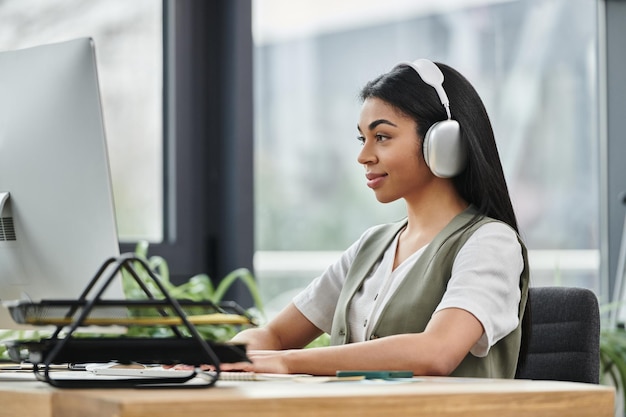 Mujer afroamericana enfocada en el uso de la computadora en el espacio de trabajo moderno