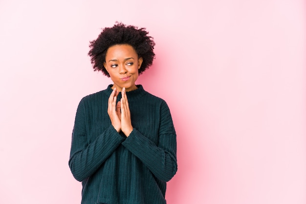 Mujer afroamericana envejecida media contra una pared rosada aislada haciendo plan en mente, creando una idea.