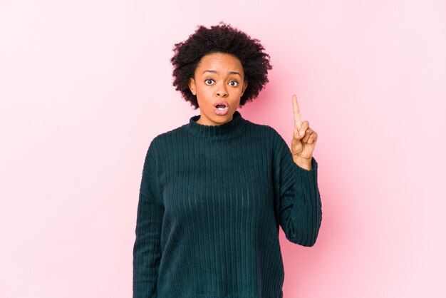 Mujer afroamericana envejecida media contra una pared rosada aislada teniendo una gran idea, concepto de creatividad.