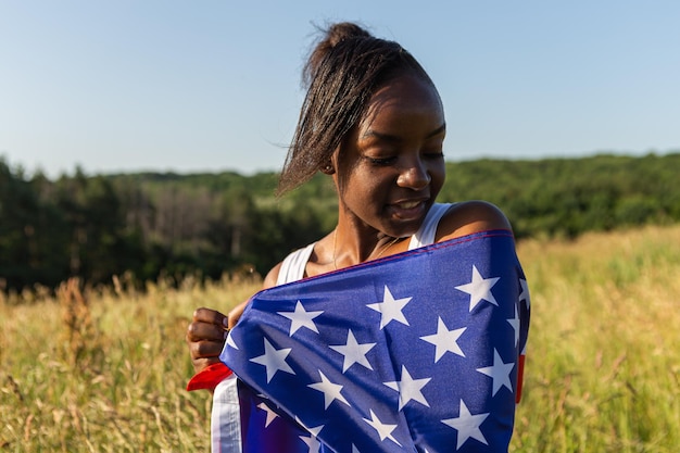 Mujer afroamericana envuelta en bandera americana