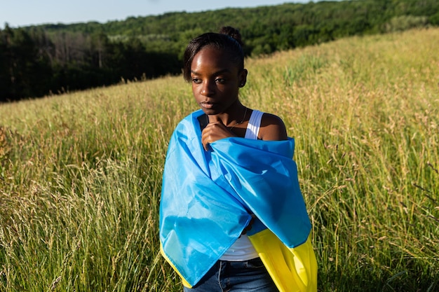Mujer afroamericana envuelta en la bandera azul amarilla ucraniana símbolo nacional de Ucrania