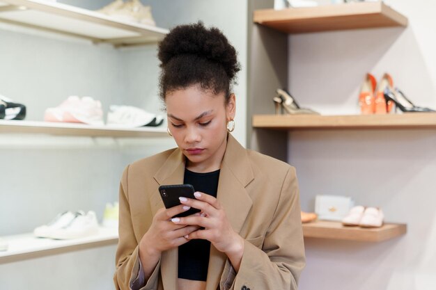 Mujer afroamericana escribe en su teléfono mientras compra