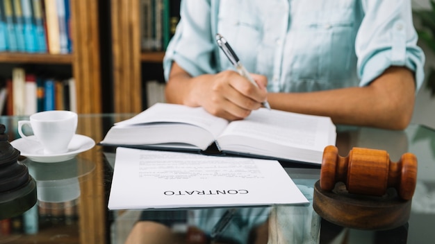 Mujer afroamericana escribiendo en el libro en la mesa con la taza y el documento