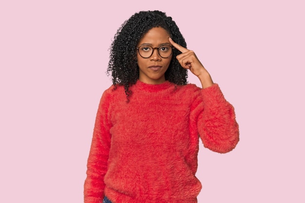 Mujer afroamericana en un estudio apuntando al templo con el dedo pensando enfocado en una tarea