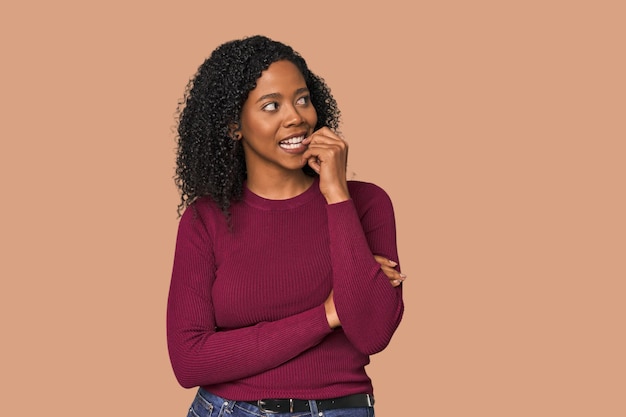 Mujer afroamericana en un estudio relajada pensando en algo mirando un espacio de copia